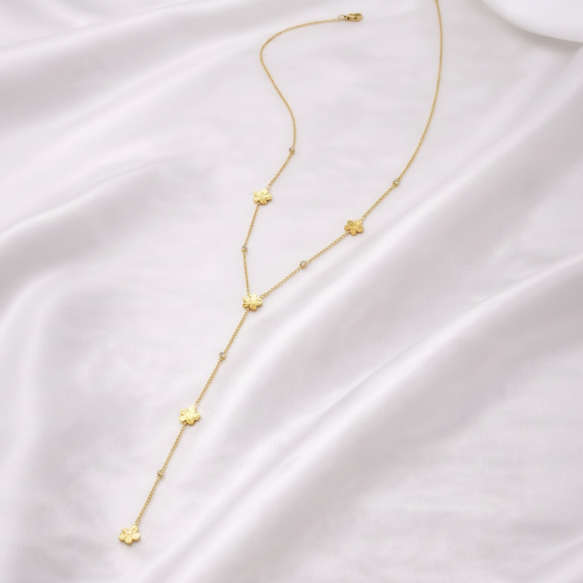 Collier Y Élina avec fleurs dorées en acier inoxydable porté sur décolleté 