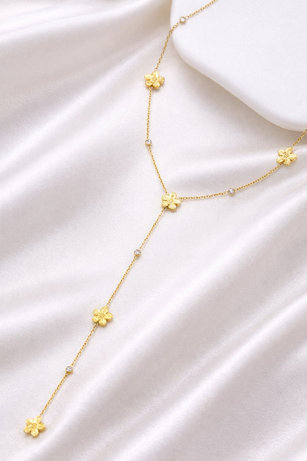 Collier Y Élina avec fleurs dorées en acier inoxydable porté sur décolleté
