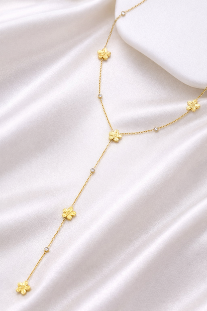 Collier Y Élina avec fleurs dorées en acier inoxydable porté sur décolleté
